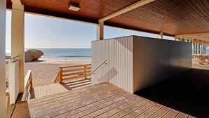 Une terrasse en bois qui mène à une plage, avec vue sur l’océan.