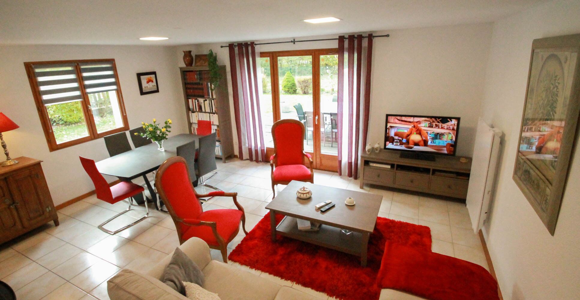 Olohuone, jossa on ruokailutila, televisio ja kirjahylly.