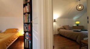 Een kleine, knusse kamer met een bed, een boekenkast en een bureau.