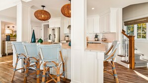 A kitchen with white cabinetry, wicker chairs, and a dining table.