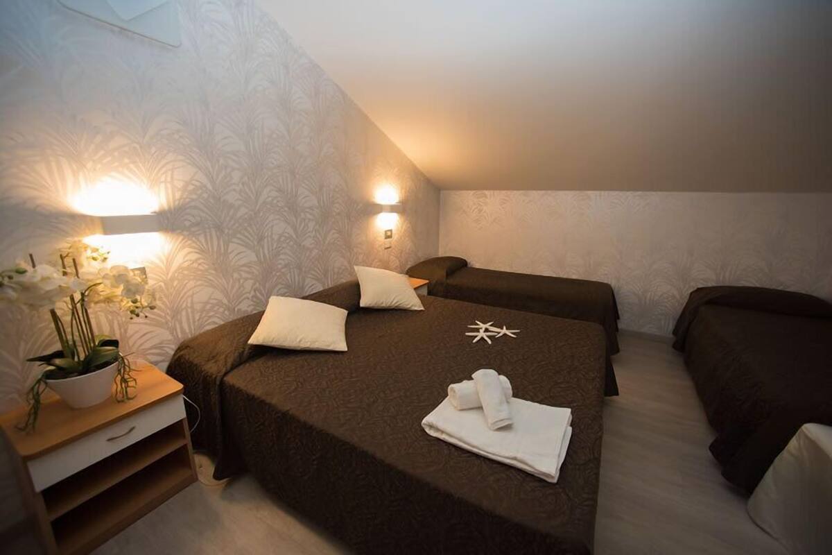 Een hotelkamer met twee bedden, een nachtkastje met een plant erop en wandlampen.