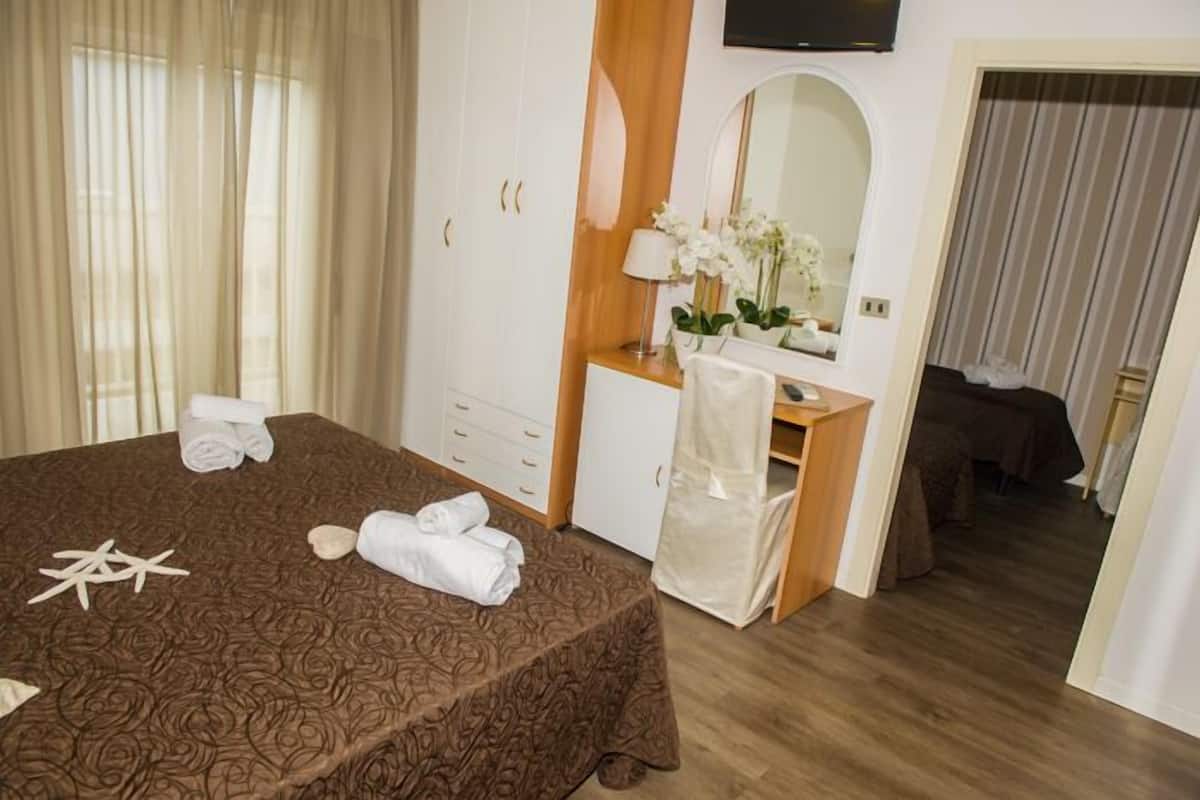 Een hotelkamer met een bed, een bureau, een spiegel en een televisie.
