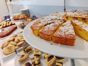 Un buffet proposant divers desserts, notamment un gâteau saupoudré de sucre glace et coupé en tranches.