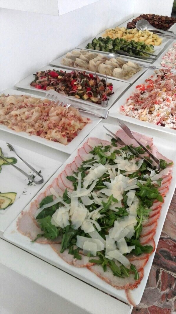 A buffet with various dishes including salads, meats, and rice.