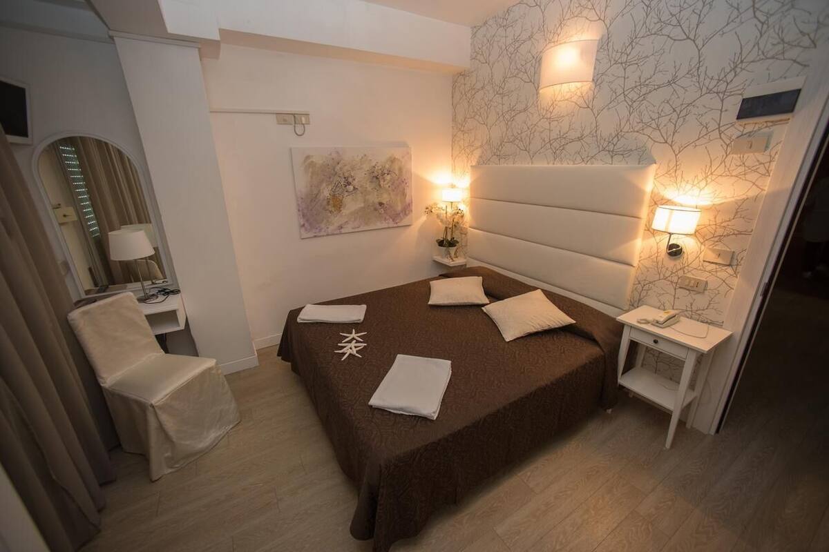 Een hotelkamer met een groot bed, een stoel, een bureau en een wandlamp.