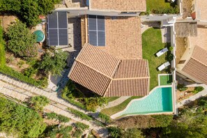 An aerial view of a resort with multiple buildings, a swimming pool, and solar panels.