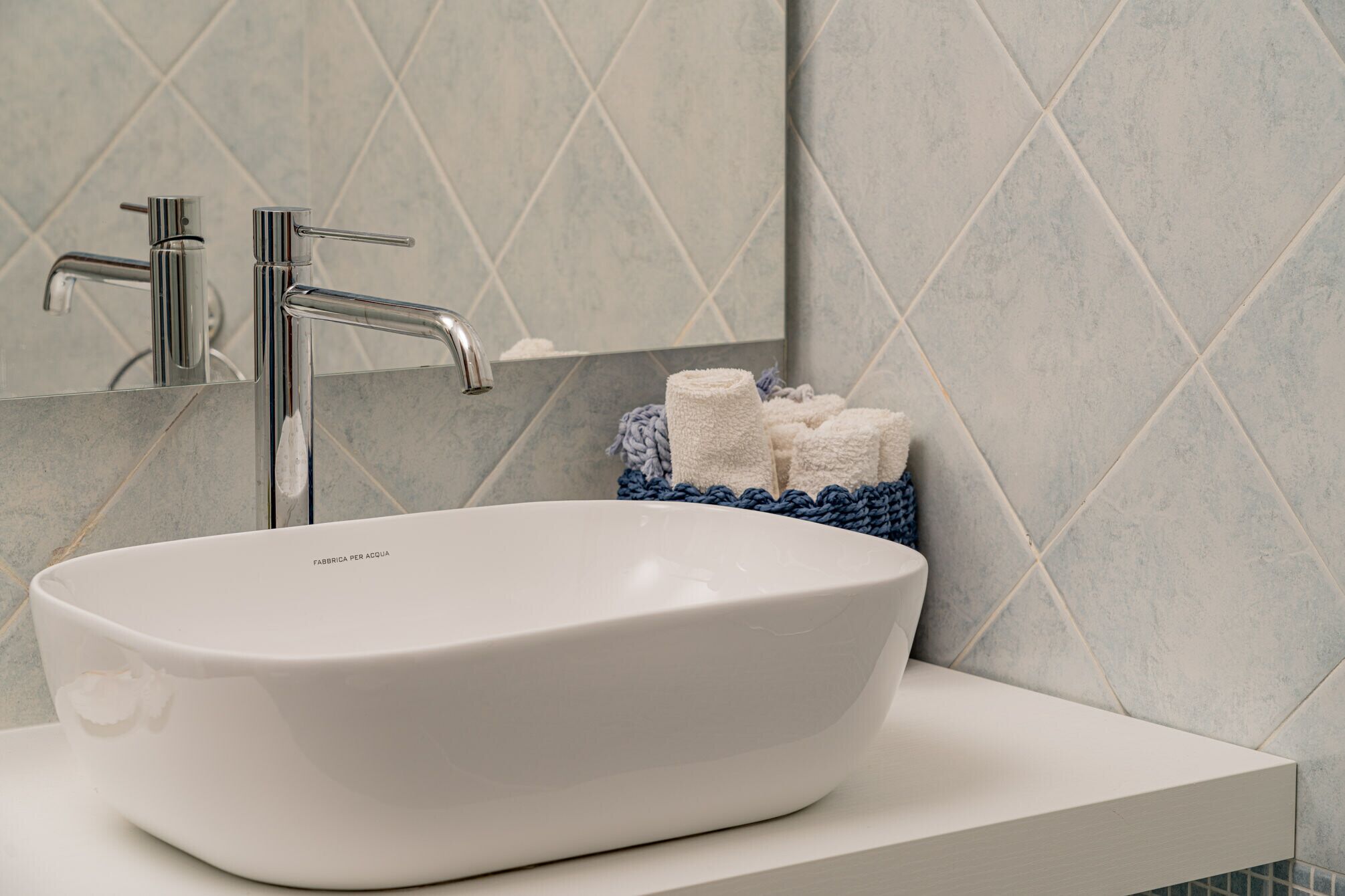 Ein Badezimmer mit Waschbecken, Armatur aus Chrom und blauem Handtuchhalter.