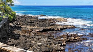 Une côte rocheuse offrant une vue dégagée sur l’océan et un bâtiment doté d’un balcon surplombant la mer.