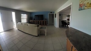 A living room with a sofa, a TV, and a dining area with a table and chairs. - Waterfront house in South Ft Myers on Whiskey creek (Fort Myers)