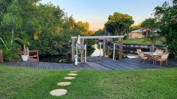 A patio area with a wooden deck, outdoor furniture, and a pergola structure. - Waterfront house in South Ft Myers on Whiskey creek (Fort Myers)