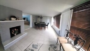 A spacious living area with a fireplace, a dining table, and a seating area with chairs. - Waterfront house in South Ft Myers on Whiskey creek (Fort Myers)