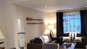 En moderne stue med et træspisebord, to sofaer, en lampe og et vindue med gardiner.