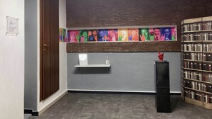 Une pièce avec une porte en bois, une bibliothèque et un mur orné d’une œuvre d’art colorée.