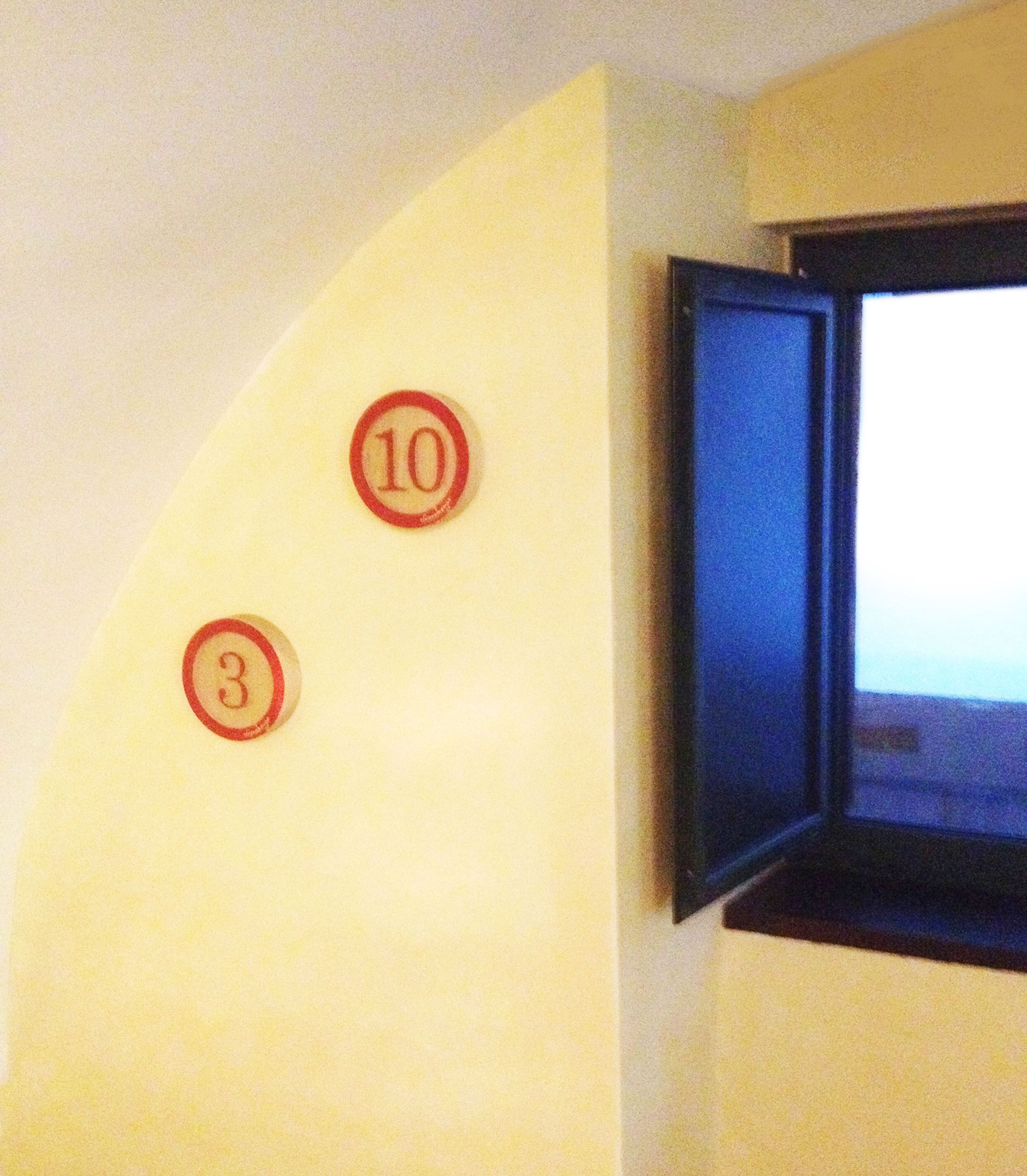 A wall with two numbered signs, 3 and 10, indicating room numbers.