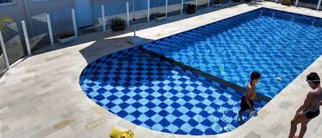 Una piscina al aire libre, sombrillas, sillones reclinables de piscina