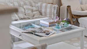 A white coffee table with a glass top, magazines, a book titled 'THOMAS DAUMONT', and two small vases with flowers. - 4 bedroom amazing home in Hornbæk (Hornbæk)
