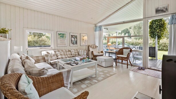 A spacious living room with a large window, a sofa set, a coffee table, and a dining area. - 4 bedroom amazing home in Hornbæk (Hornbæk)