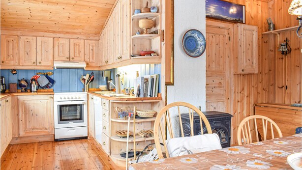 A cozy kitchen with wooden cabinets, a stove, and a dining area with a table set for two.