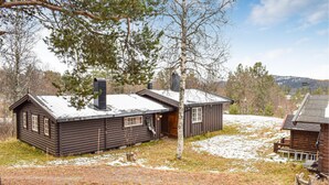 A rustic cabin with a chimney, a small porch, and a wooden deck.