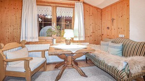 Une pièce chaleureuse avec des murs en bois, une table en bois, un canapé et une chaise.
