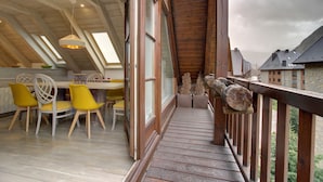 Une terrasse en bois avec un espace repas comprenant des chaises jaunes et une table.