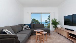 A modern living room with a grey sectional sofa, a small round table, and a TV on a wooden stand.