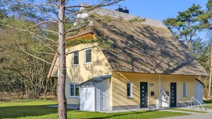 Et hus med stråtækt tag, en lille veranda og en garage.