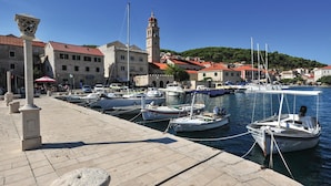 A marina with boats docked, a prominent tower, and buildings with red roofs. - Cozy home in Pucisca with private swimming pool, can be inside or outside (Pucisca)