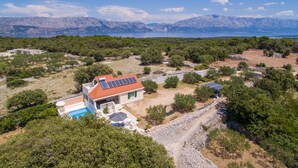 A house with a red roof and solar panels, surrounded by trees and a rocky landscape with mountains in the background. - Cozy home in Pucisca with private swimming pool, can be inside or outside (Pucisca)