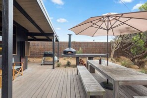 An outdoor patio with a pizza oven, a table, and a large umbrella. - Barefoot in Blairgowrie (Blairgowrie)
