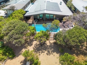 A modern house with a swimming pool surrounded by trees.
