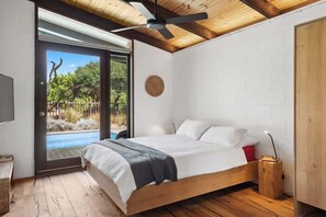 A bedroom with a bed, a ceiling fan, a wooden floor, and a view of an outdoor swimming pool. - Barefoot in Blairgowrie (Blairgowrie)