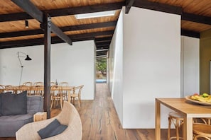A modern interior with a dining area, a sofa, and a table with fruit.
