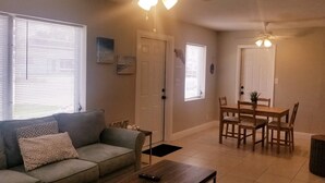 Un salon avec un canapé, une table à manger et des chaises, un ventilateur de plafond et une cheminée.