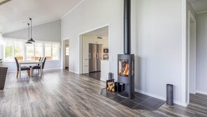 A spacious living area with a large fireplace, wooden flooring, and a dining area with chairs and a table.