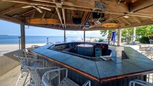 Un espace bar avec vue sur l’océan, un plafond en bois et des tabourets de bar.