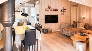 A cozy living space with a fireplace, a dining area, and a TV mounted on the wall. - Amazing home in ålbæk with WiFi (Ålbæk)
