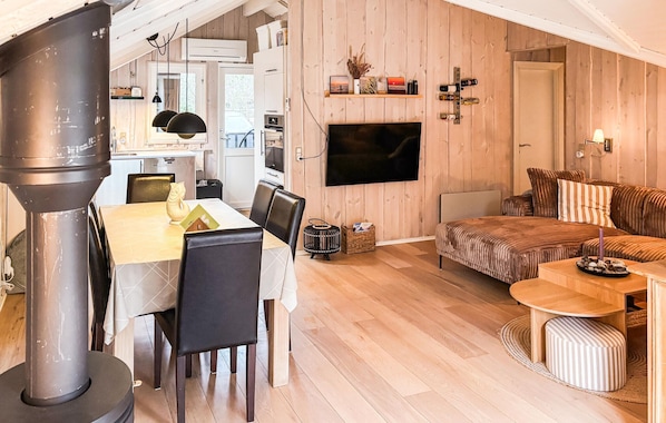 Un espacio habitable acogedor con chimenea, una zona de comedor y un televisor montado en la pared.