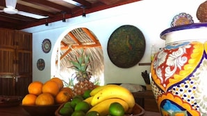 A room with wooden furniture, a bowl of fruit, and a decorative vase. - Hacienda la Rusa (Barra de Potosi)