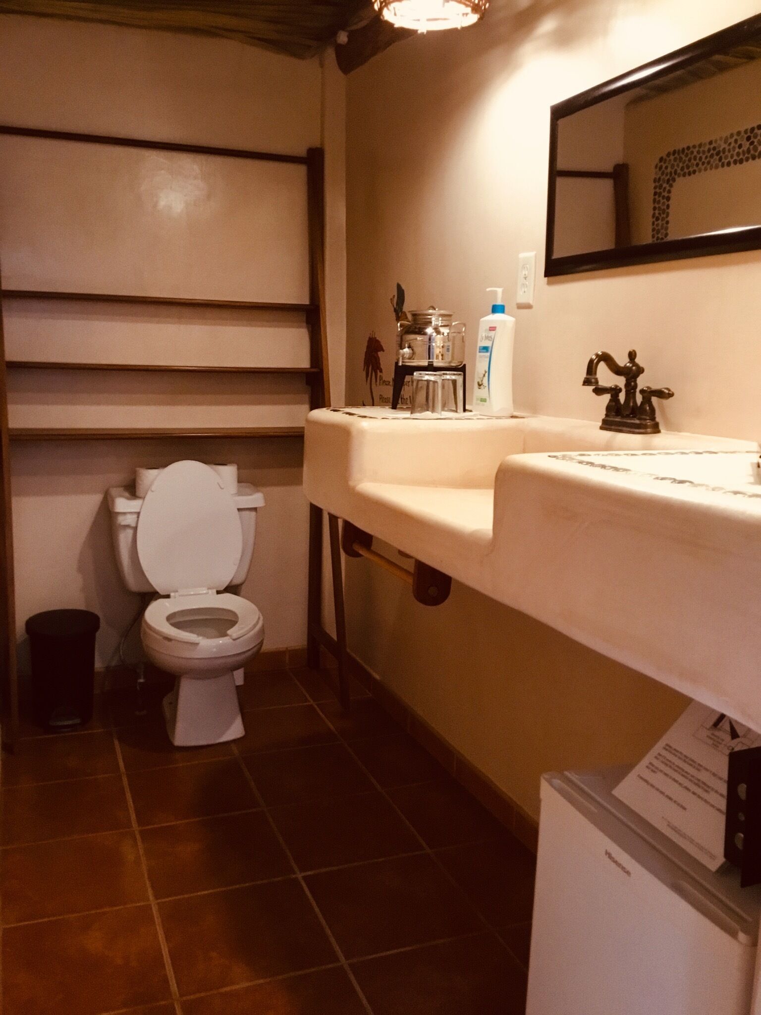Un baño con inodoro, lavamanos y un cubo de basura.