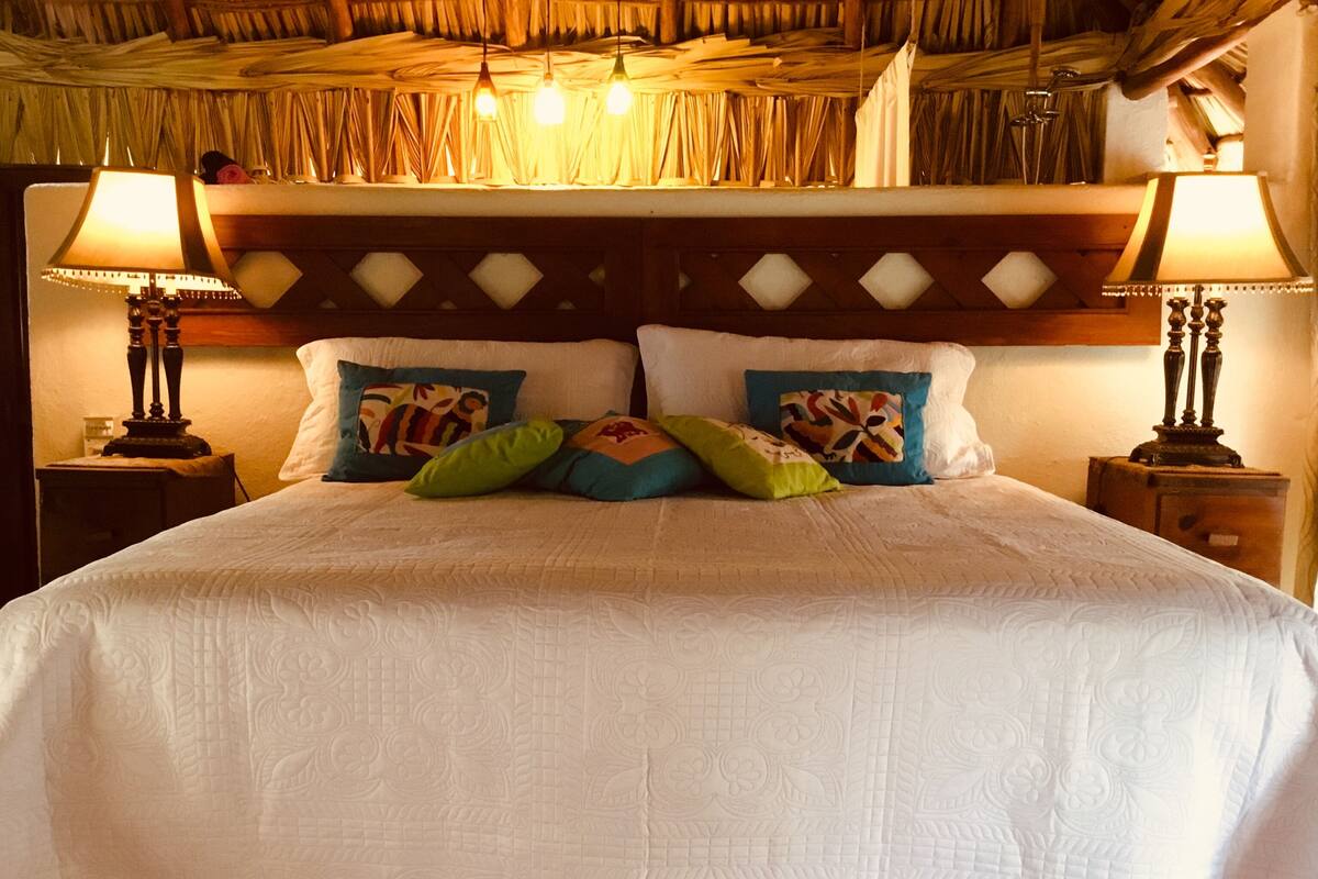 A bed with a white quilt, two nightstands, and two lamps.