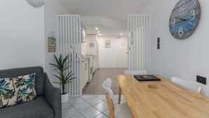 Ein modernes Interieur mit Essbereich, einer Couch, einer Uhr und einer Küche im Hintergrund.