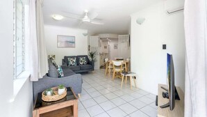 Ein modernes Wohnzimmer mit einer Couch, einem Esstisch und einem Fernseher.