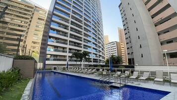 A modern hotel with a swimming pool, surrounded by high-rise buildings.
