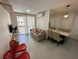 A modern living room with a sofa, dining table, chairs, and a TV.