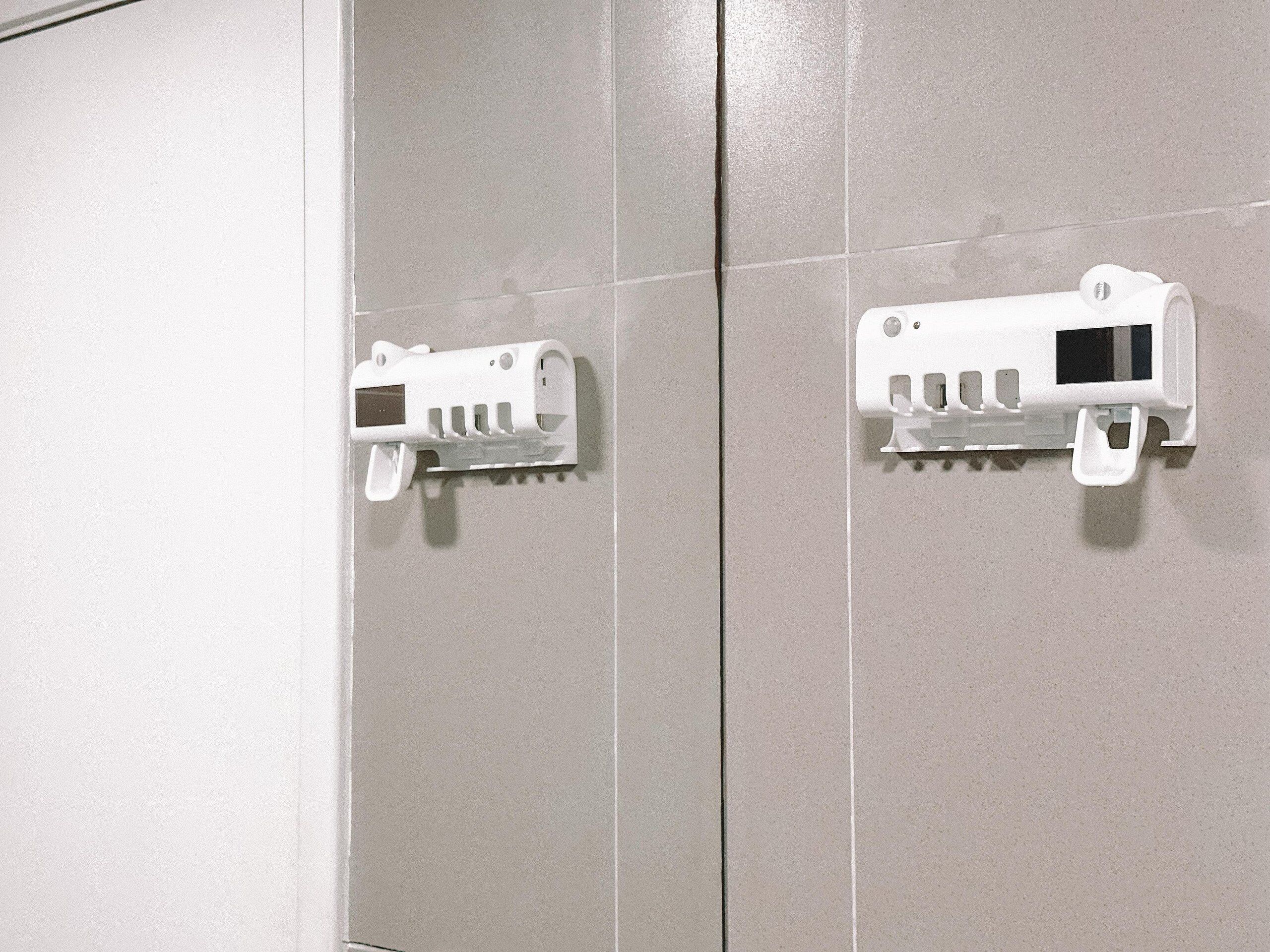 A bathroom with two white towel dispensers mounted on a tiled wall.