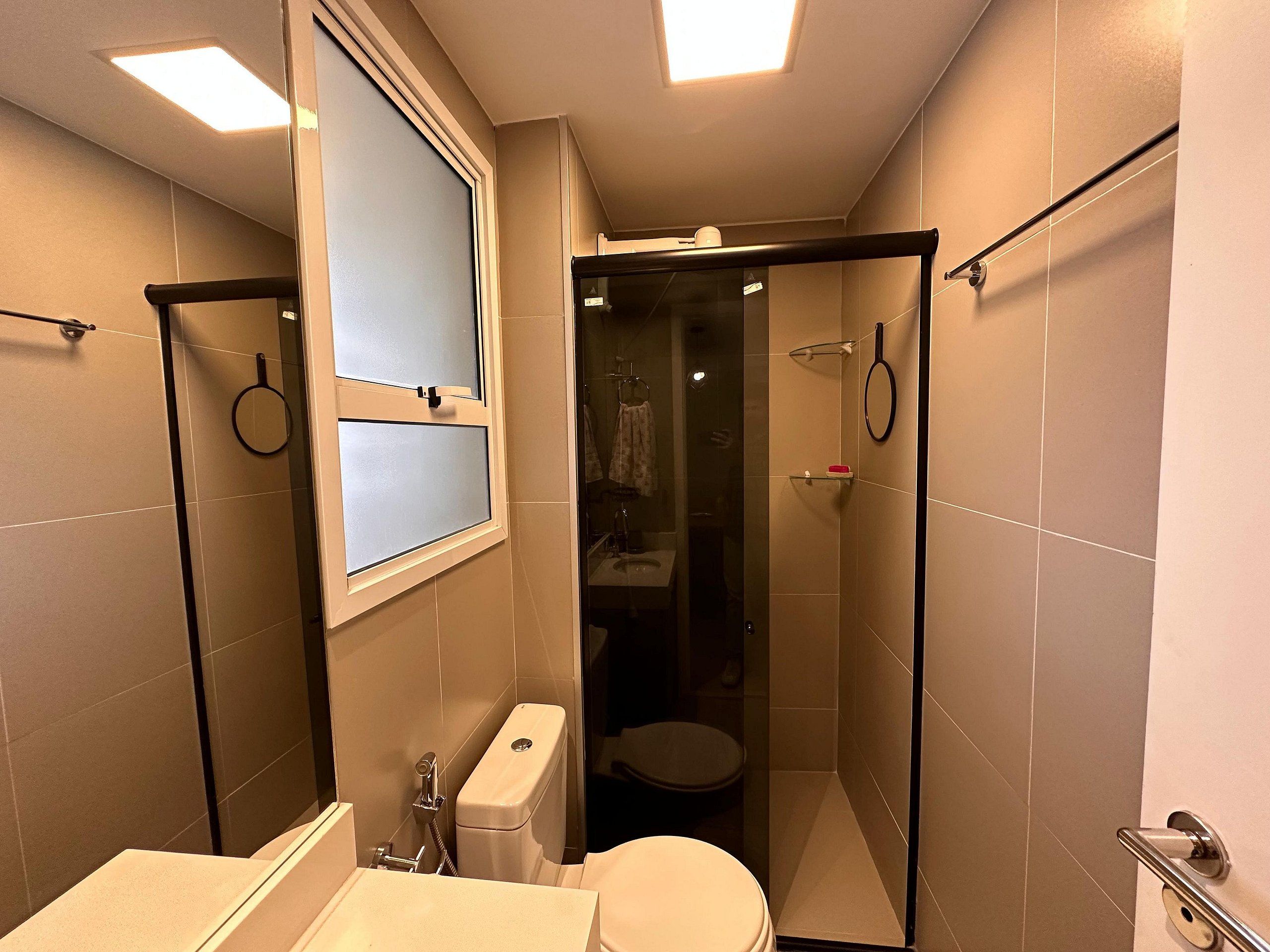Un baño pequeño con inodoro, cabina de ducha y ventana con vidrio esmerilado.
