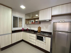 A modern kitchen with a built-in microwave, gas stove, and stainless steel refrigerator. - Compacto de Luxo - Helbor My Way (Fortaleza)