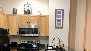 Une cuisine de taille réduite, dotée de meubles en bois, d’appareils électroménagers en acier inoxydable et d’un petit îlot central.
