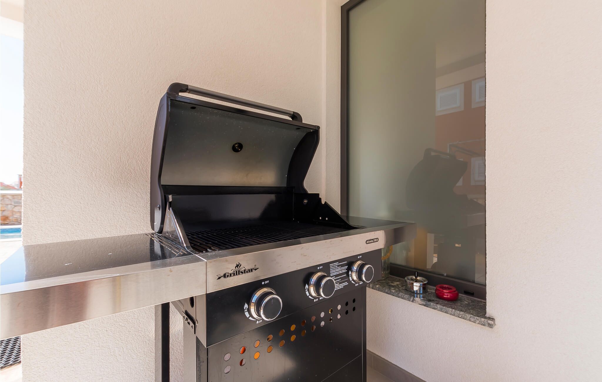 A portable grill with controls and a window for ventilation, placed on a balcony.